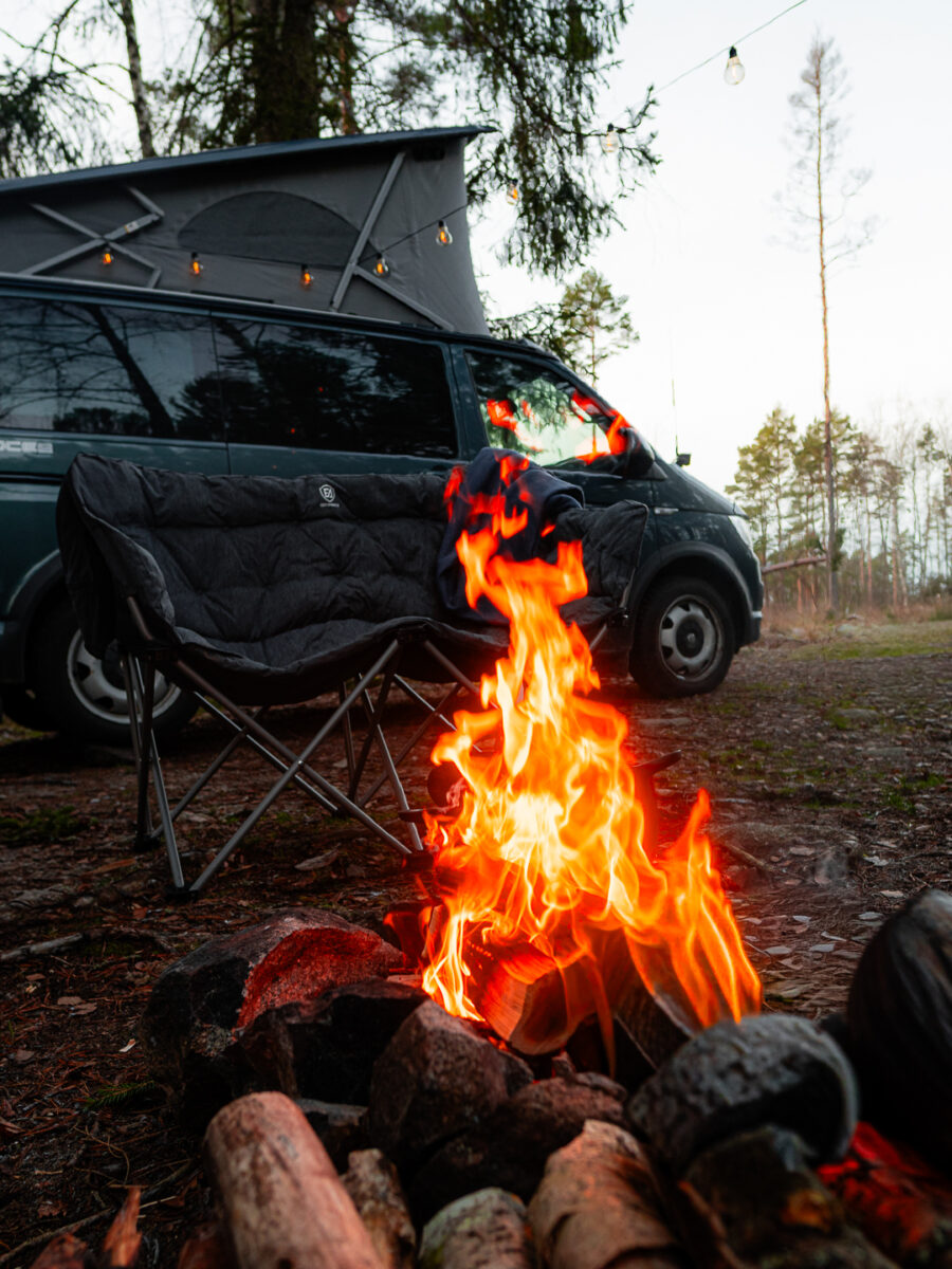 Lägereld framför en VW California med ljusslinga i poptoppen
