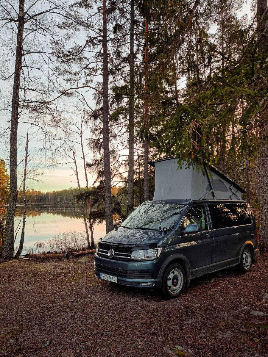 VW California med poptoppen uppe vid en skogssjö en höstdag