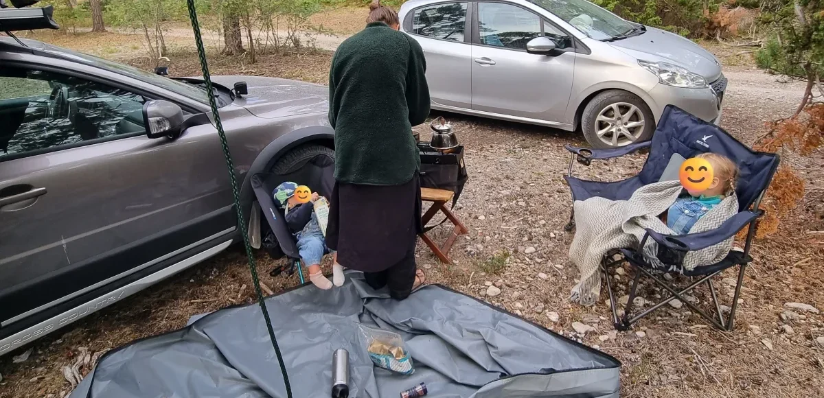 Frukostbestyr utanför bilen med taktältet uppfällt ovanför