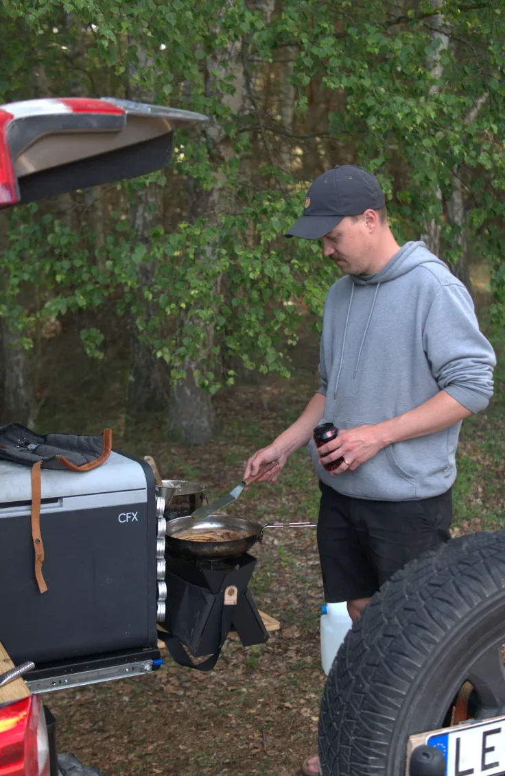 någon som steker korv och lagar risotto på en campingkök
