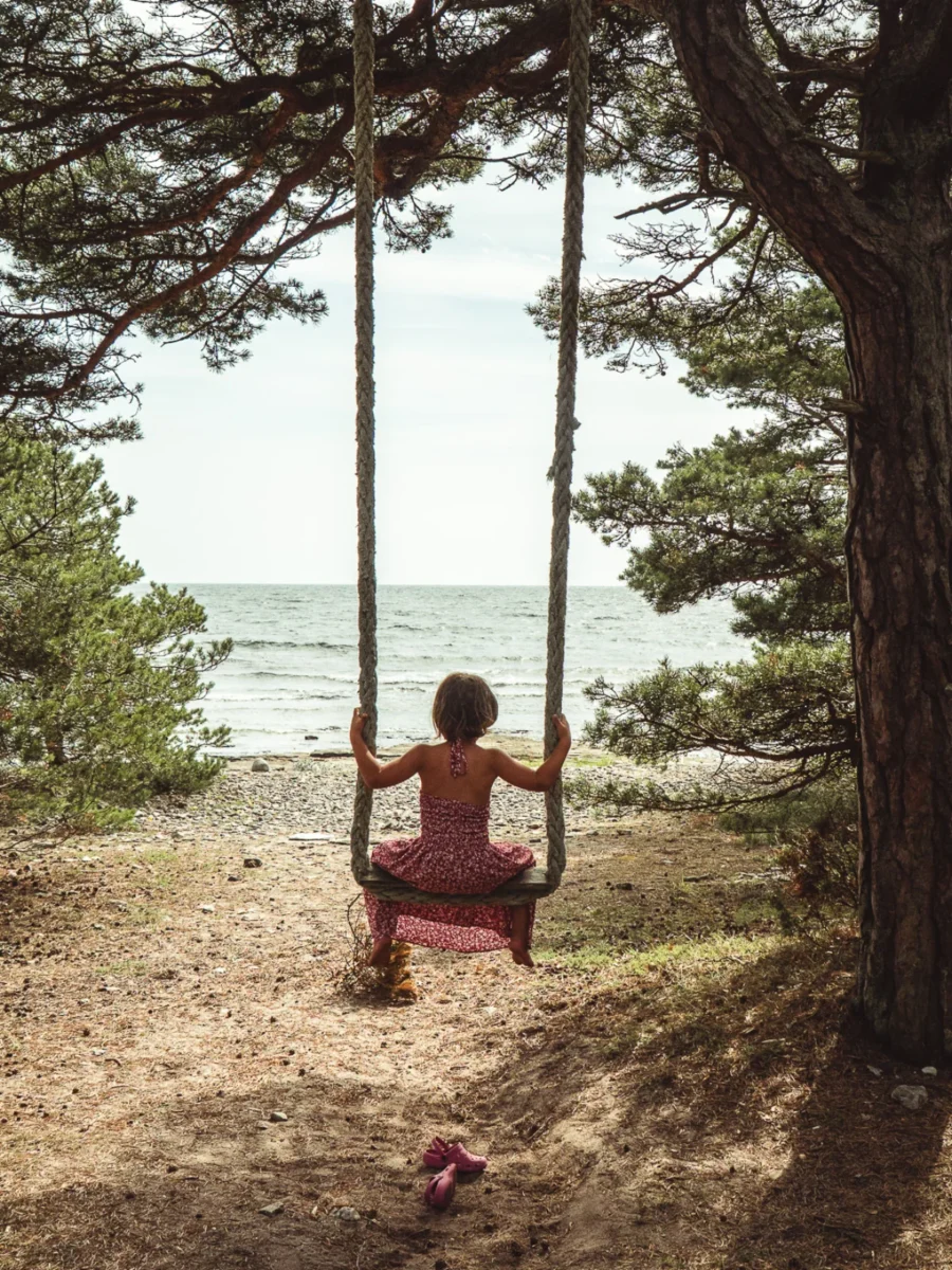Barn i en repgunga under tallarna med utsikt mot havet