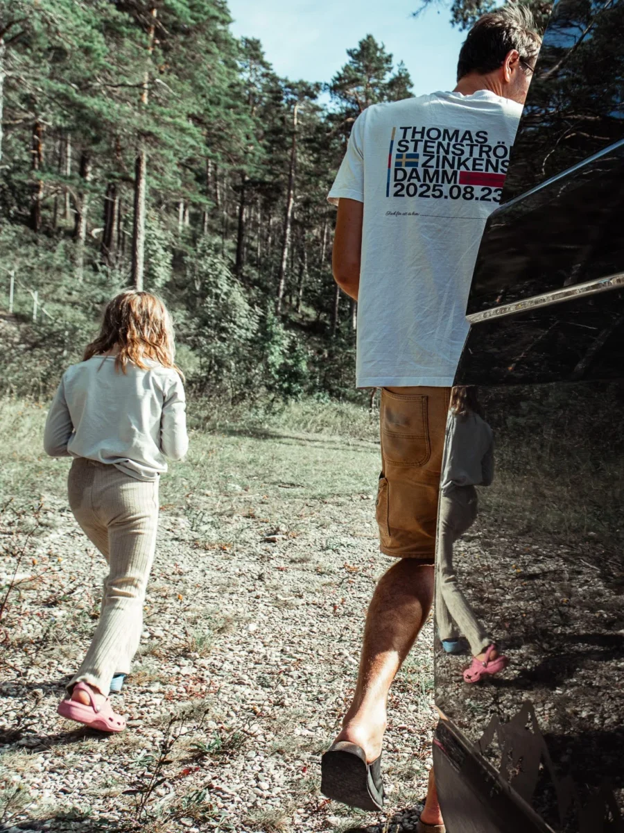 Pappa och barn bakifrån på väg in i tallskogen från campingplatsen