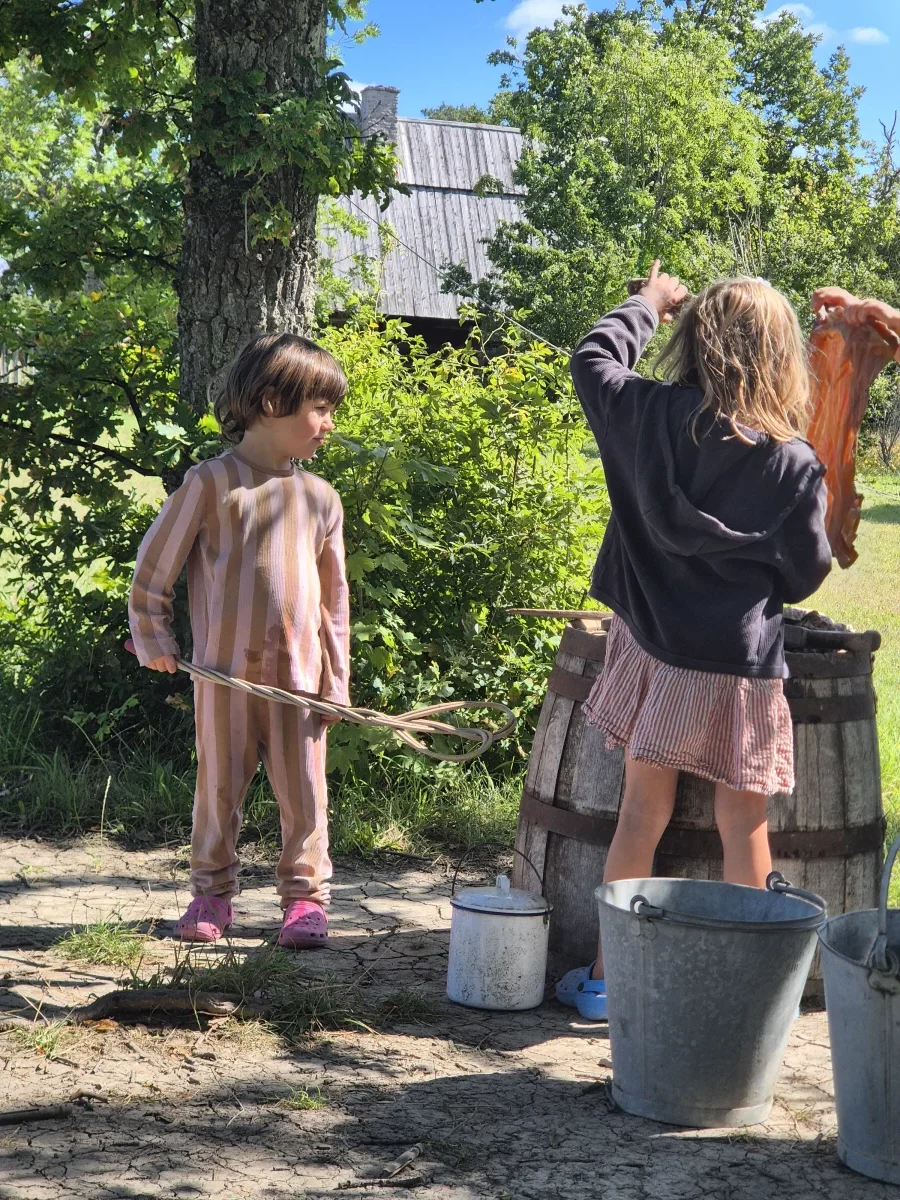 Två barn bykar tvätt i en träbalja på Bungemuseet