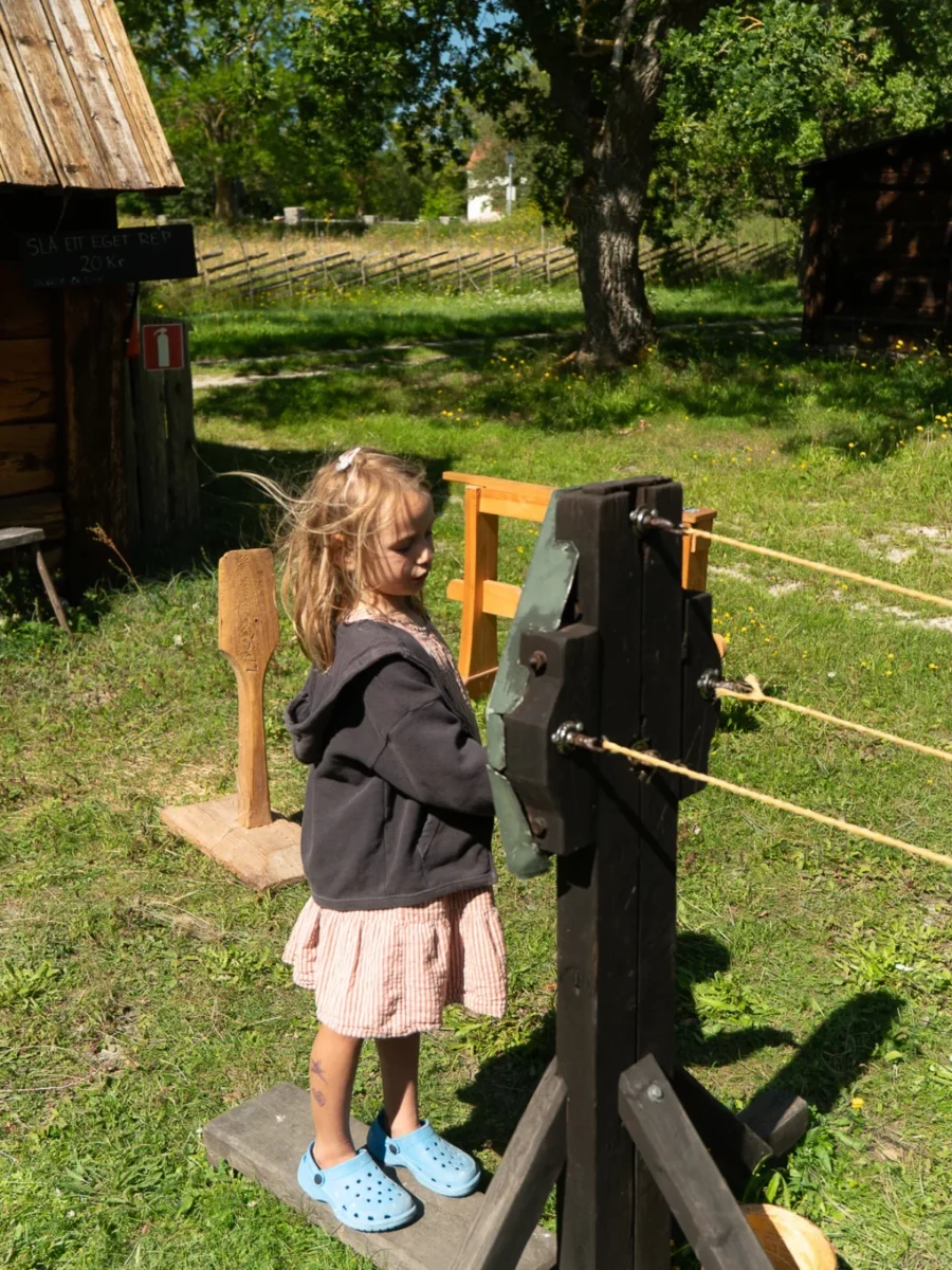 Barn vevar en gammal repslagarmaskin av trä på Bungemuseet