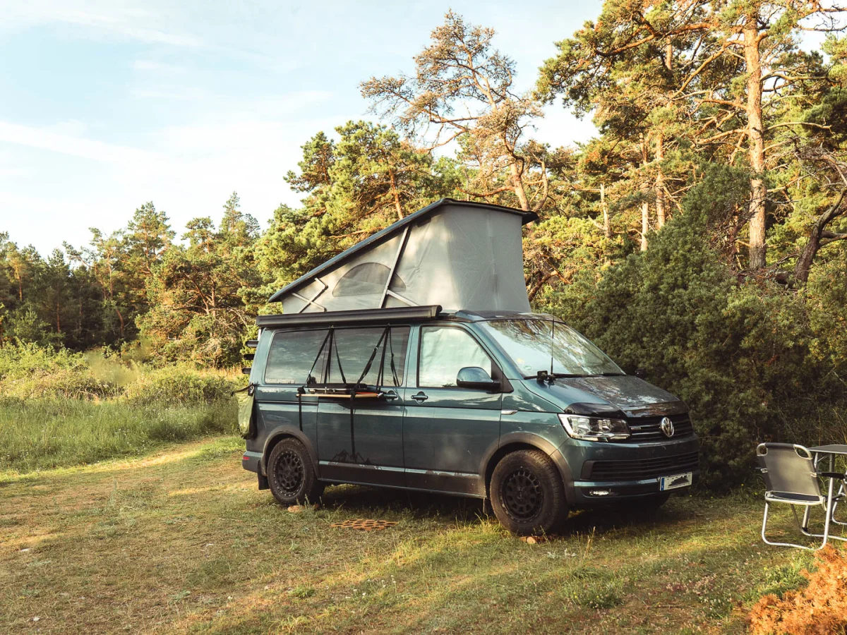 Campervan med poptoppen uppe på en gräsplätt vid skogskanten på Gotland