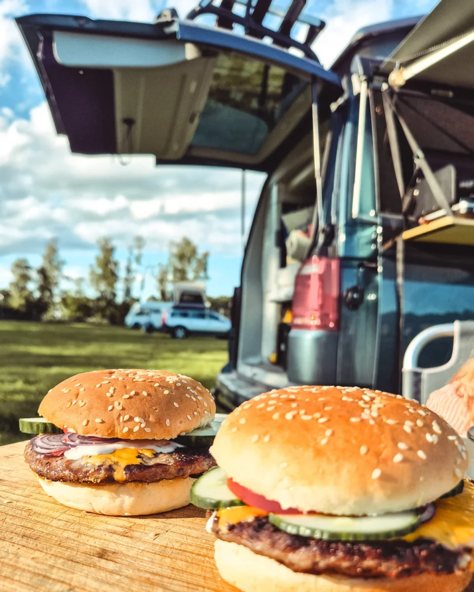 Hamburgare på en skärbräda framför vanens öppna baklucka