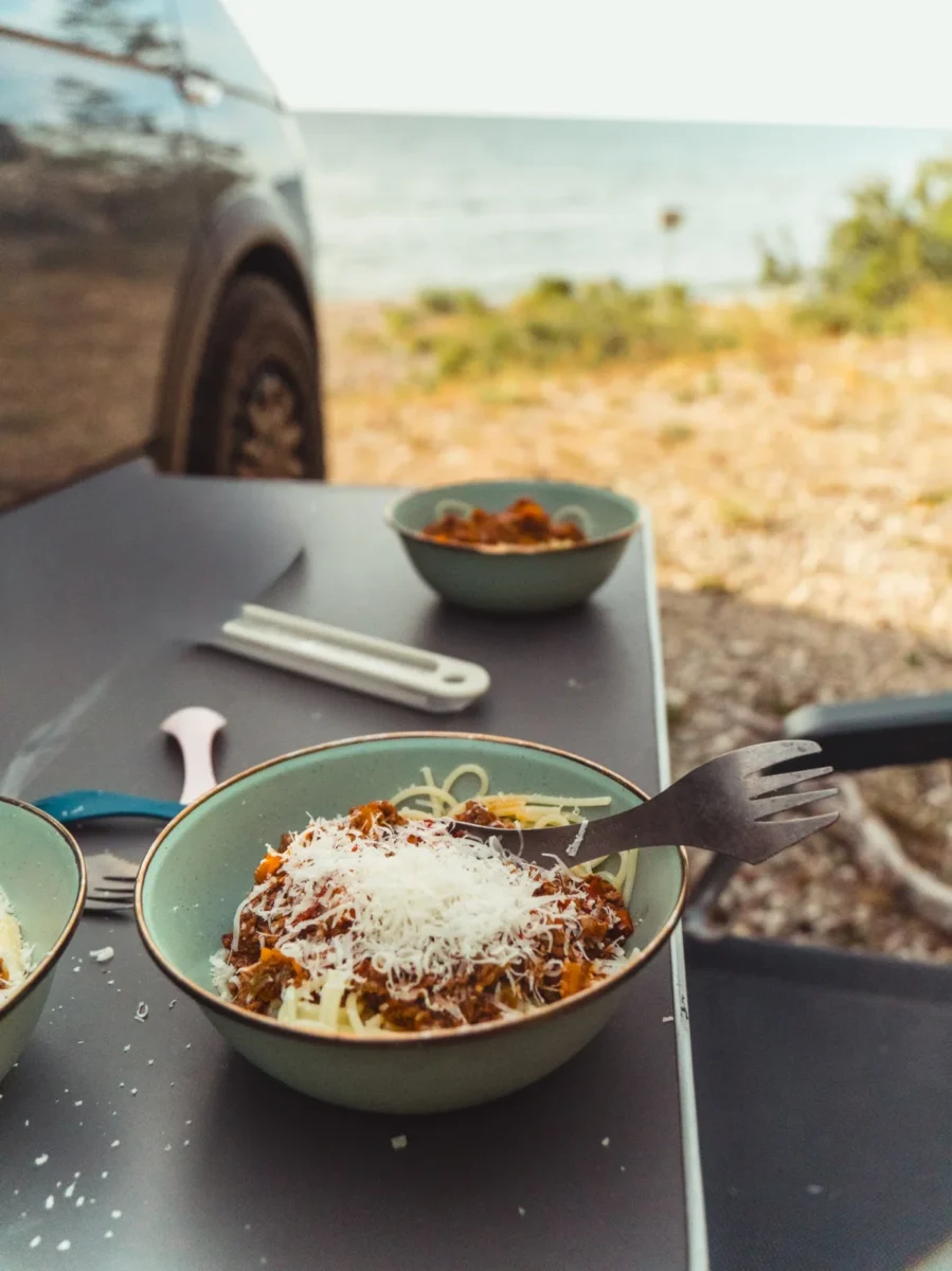 Spaghetti och köttfärssås på bordet utanför vanen med havet i bakgrunden