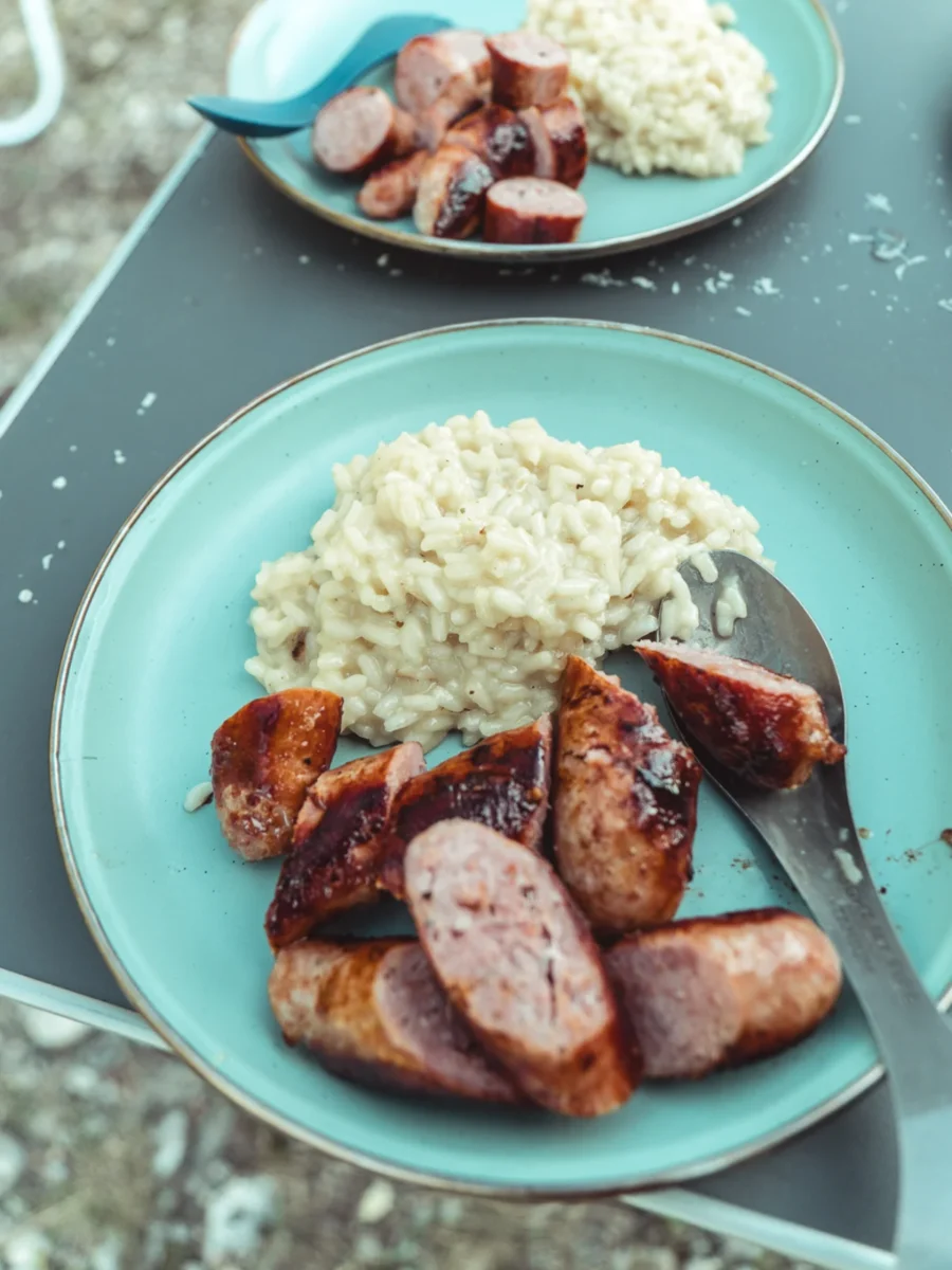 Risotto och stekt salsiccia på en tallrik vid stranden