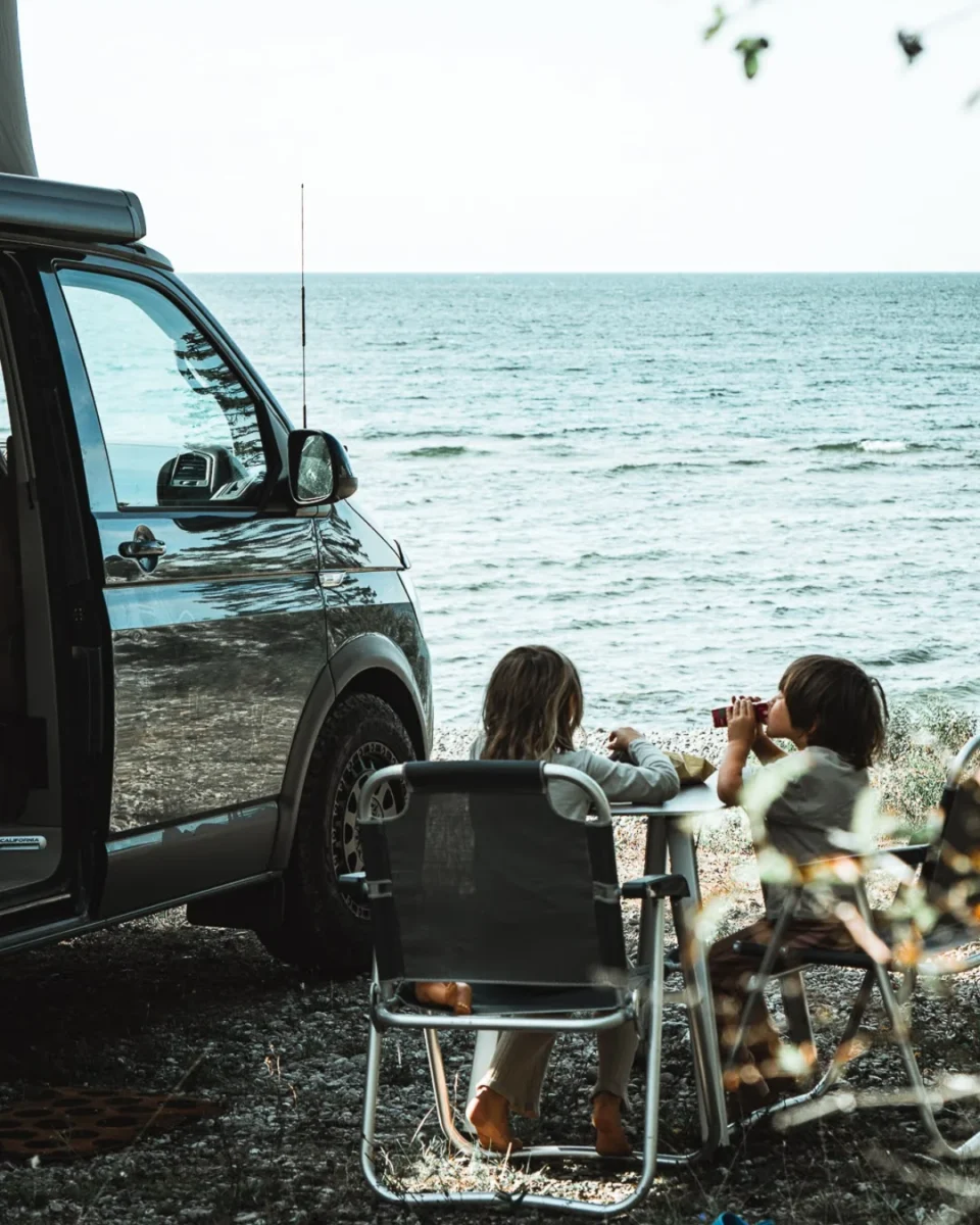 Barnen äter i campingstolar bredvid vanen vid havet