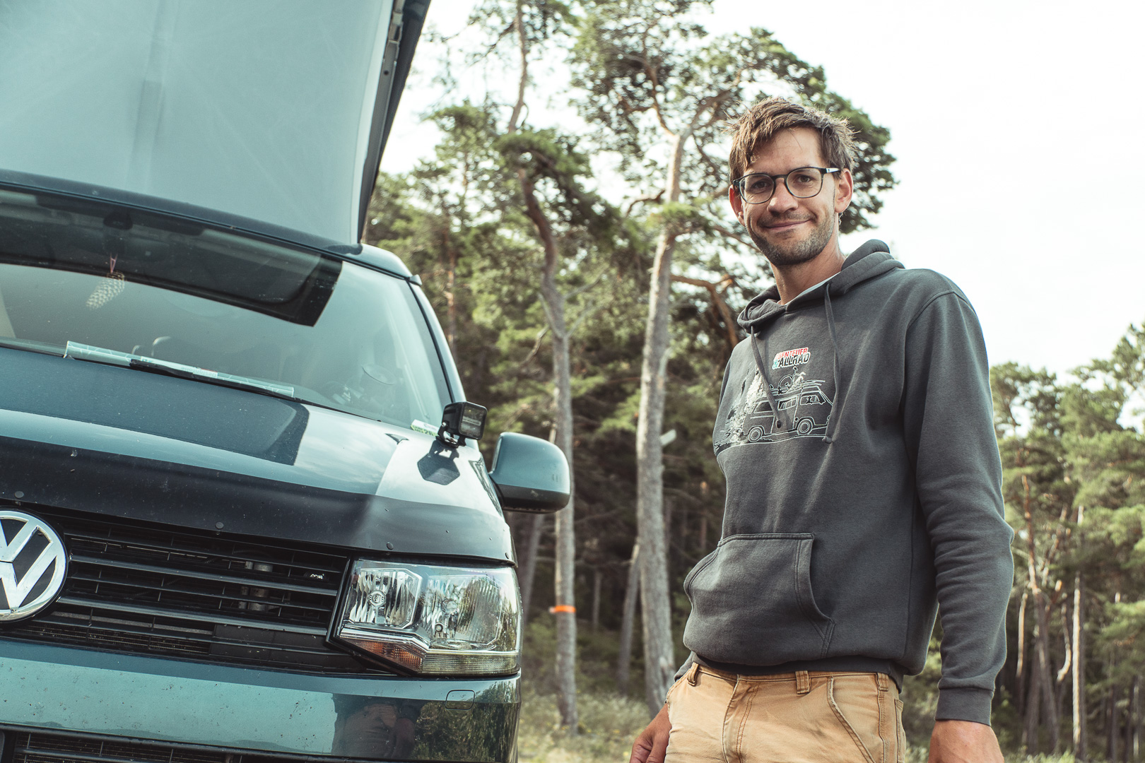 Campervan med poptoppen uppe bland tallarna vid en stenstrand på Gotland
